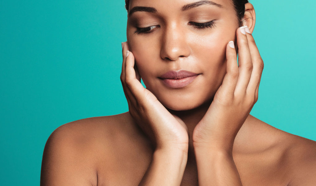 Lumecca IPL photofacial London - woman touching her face against a teal background Woman touching her face against a teal background for Lumecca IPL photofacial in London